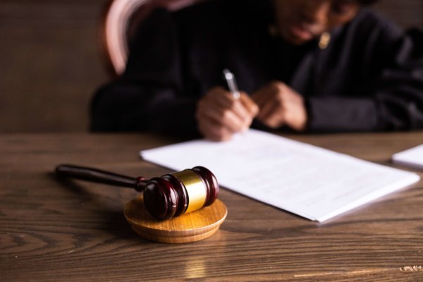 Gavel With A Man Working On Some Papers In Backgrounds